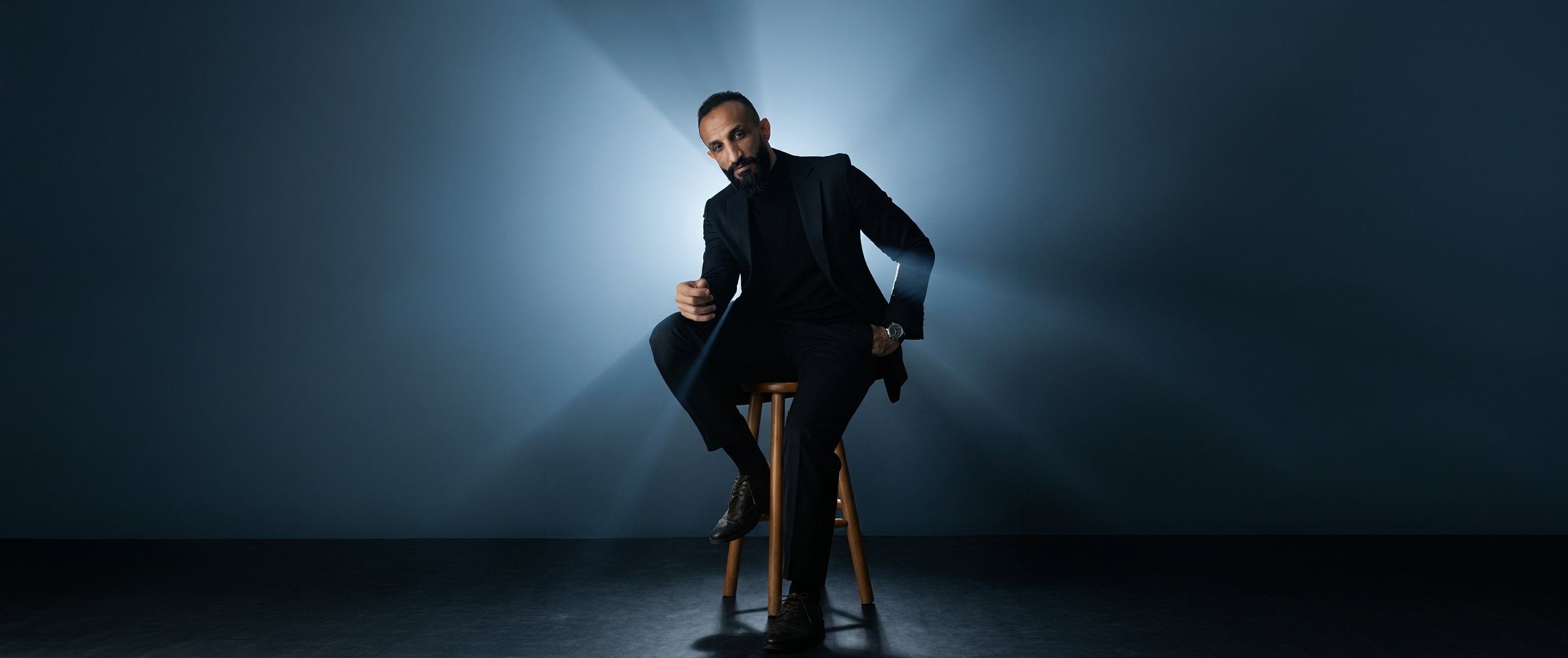 ياسر سعد — متخصص ما بعد الإنتاج، جالس في استوديو بإضاءة سينمائية زرقاء